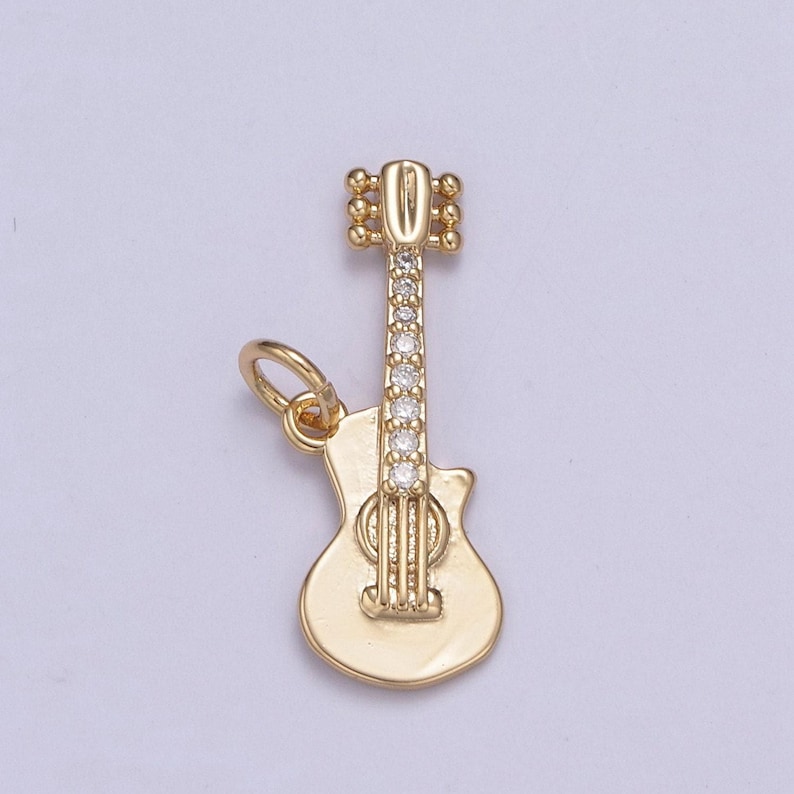 May include: Gold-tone guitar charm with clear crystal accents. The charm has a loop for attaching to a necklace or bracelet.
