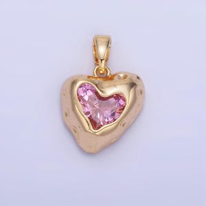 May include: A gold heart-shaped pendant with a pink crystal in the center.
