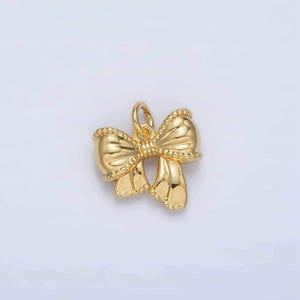 May include: A gold-colored bow charm with a beaded edge. The charm is designed to be used for jewelry making.
