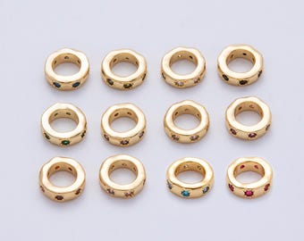 May include: A collection of twelve gold-colored, circular beads. Each bead has a central hole and is adorned with small, colorful gemstones. The gemstones are in various colors, including blue, green, and red, adding a touch of sparkle.