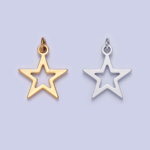 May include: Two star-shaped charms, one gold and one silver, with a hollow center. Both charms have a loop at the top for attaching to a necklace or bracelet.