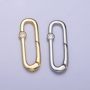 May include: Two metal clasps with a clear rhinestone in the center. One clasp is gold and the other is silver.