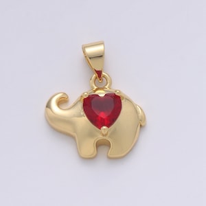 May include: Gold-tone elephant pendant with a red heart-shaped gemstone. The pendant is a charm for a necklace or bracelet.