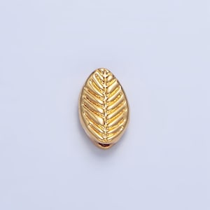May include: A gold leaf-shaped bead with a textured design. The bead is perfect for jewelry making or crafting.