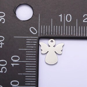 May include: A silver angel charm with a hole at the top for attaching to a necklace or bracelet. The charm is about 1 cm tall.