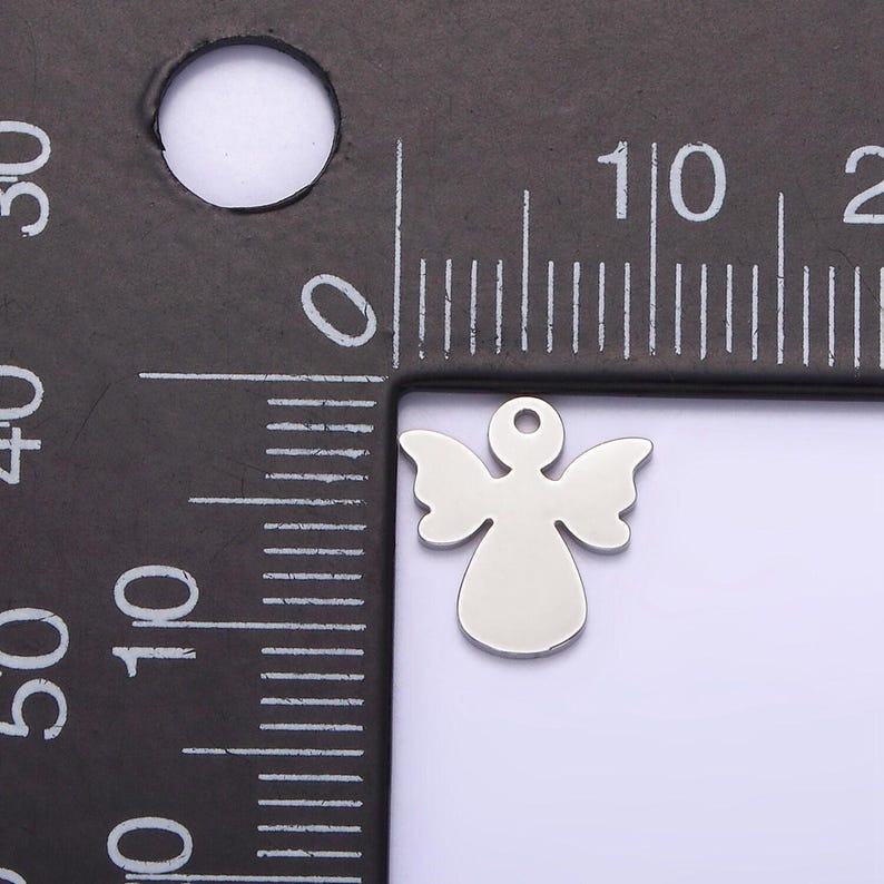 May include: A silver angel charm with a hole at the top for attaching to a necklace or bracelet. The charm is about 1 cm tall.