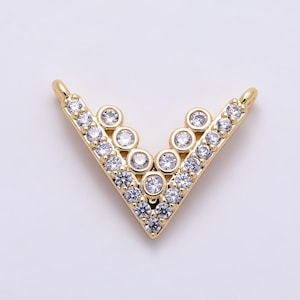 May include: A V-shaped gold jewelry connector featuring a series of clear, round-cut cubic zirconia stones set along the frame. The piece includes two small loops at the top ends for attachment, with a polished gold finish throughout.