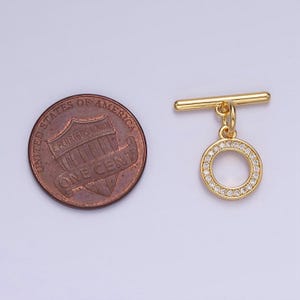 Pode incluir: Fecho de correr dourado com um pingente redondo incrustado com strass transparentes. O pingente &eacute; aproximadamente do tamanho de uma moeda de um centavo de d&oacute;lar americano.