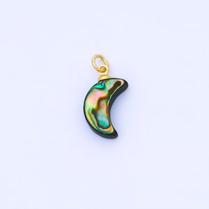 May include: A crescent moon pendant with a gold-colored bail. The pendant features iridescent abalone shell with hues of green, pink, and gold, set against a black background. This jewelry item is suitable for necklaces and other accessories.