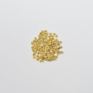 May include: A pile of gold-coloured metal jump rings, used for connecting jewellery chains and other components.