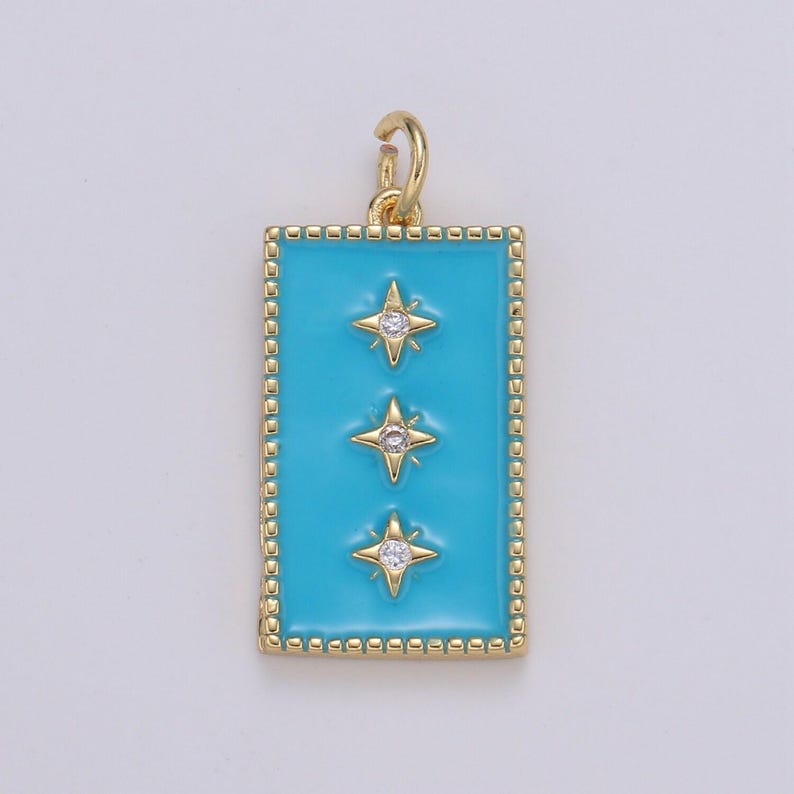 May include: A gold pendant charm with a turquoise blue enamel rectangle and three gold stars with clear rhinestones.