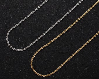 May include: Two gold and silver rope chains on a black background. The chains are laid out in a parallel fashion.