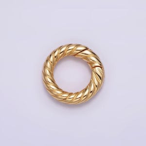 May include: A gold-toned metal ring with a twisted rope design. The ring is open and has a smooth, polished finish.