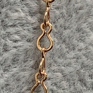Op de afbeelding: Close-up van een gouden ketting met een delicaat, figuur-acht schakels ontwerp.
