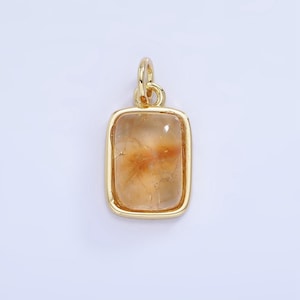 May include: A gold pendant featuring a rectangular clear quartz stone with brown inclusions. The pendant is displayed against a white backdrop.