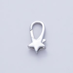 May include: A silver-colored lobster clasp with a star-shaped base. The clasp is designed to secure jewelry or other accessories. The star has five points and is polished to a high shine. The clasp is shown against a light background.
