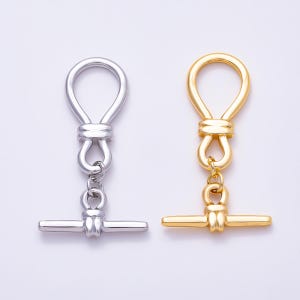 May include: Two toggle clasps for jewelry making, one in a polished silver tone and one in a polished gold tone. Each clasp features a circular ring connected to a horizontal bar by a series of smaller, looped metal links and knots.