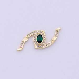 May include: Gold-tone eye-shaped clasp with a green gemstone surrounded by clear rhinestones.