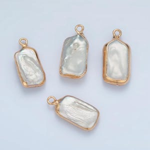 May include: Four gold-toned pendants with white baroque pearl inserts. The pendants are rectangular in shape with a slightly irregular edge.