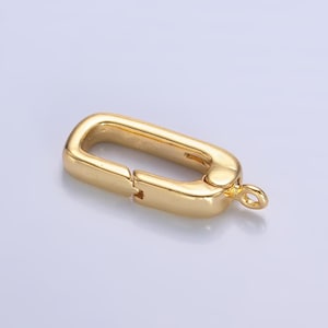 May include: Gold-toned metal clasp with a rectangular shape and a spring-loaded closure. The clasp has a small loop on one end for attaching to a chain or cord.