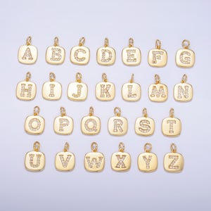 May include: A set of 26 gold-tone charms, each featuring a letter of the alphabet, adorned with clear sparkling rhinestones. The charms are square-shaped and have a loop at the top for attaching to jewelry.