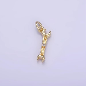 May include: A gold-toned wrench charm with a single clear rhinestone. The charm has a loop at the top for attaching to a necklace or bracelet.