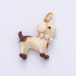 May include: A gold-toned dog charm with a cream-colored body, brown spots, and a pearl necklace. The charm has a gold loop for attaching to a necklace or bracelet. The dog's features include black eyes and brown paws.