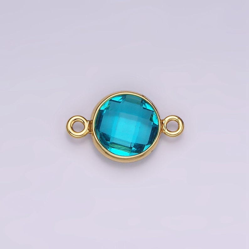 Puede incluir: Conector dorado con una piedra preciosa redonda y facetada de color azul turquesa.