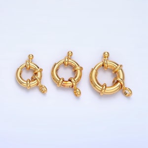 May include: Three gold-toned metal ring clasps of different sizes. The clasps are round and have a smooth, polished finish.