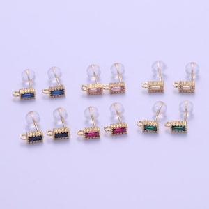May include: Assortment of gold-tone earring findings with various colored rectangular gemstones. The findings are displayed on a white surface.