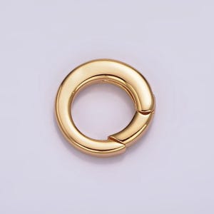 Pode incluir: Um anel de metal dourado com uma superf&iacute;cie lisa e arredondada. O anel &eacute; aberto de um lado e tem um fecho com dobradi&ccedil;a.