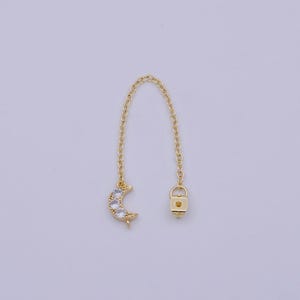 May include: Gold chain extender with a crescent moon charm featuring clear cubic zirconia stones. The extender has a lobster clasp.