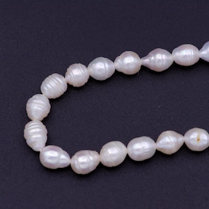 May include: A strand of white freshwater pearls, strung together to form a necklace. The pearls are oval-shaped and have a smooth, glossy finish.