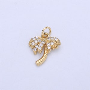 May include: Gold palm tree charm with clear crystal accents. The charm has a loop at the top for attaching to a necklace or bracelet.