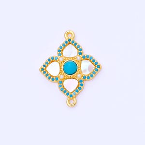 Op de afbeelding: Een goudkleurige, vierbladige bedel met een turquoise middensteen. Elk bloemblad heeft een witte, parelmoersteen en is omrand met kleine, turquoise kralen. Kleine gouden lussen aan de boven- en onderkant.