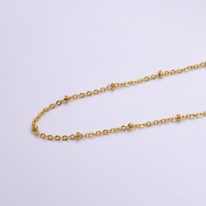 May include: A gold chain necklace with small round beads.