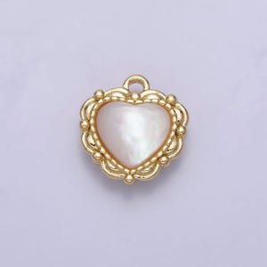 May include: A gold heart-shaped pendant with a white mother-of-pearl inlay. The pendant has a detailed, ornate design around the edge.