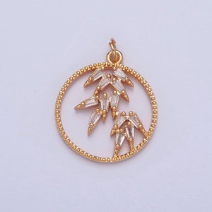 May include: Gold pendant with a circle design featuring a stylized bamboo branch with clear crystal accents.