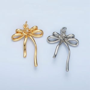 May include: Two gold and silver bow charms with a rhinestone in the center of each bow.