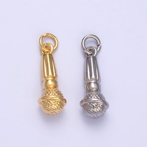 May include: Two gold and silver microphone charms. The charms are detailed with a textured microphone head and a smooth, ridged body. The charms have a loop at the top for attaching to a necklace or bracelet.