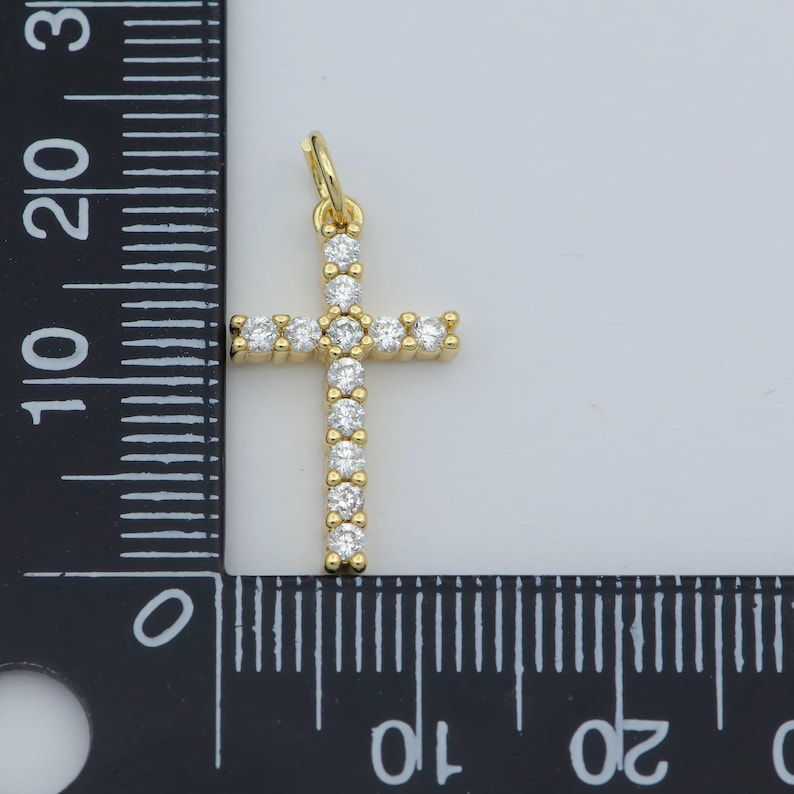 Puede incluir: Un colgante de cruz de oro con piedras de circonita c&uacute;bica transparentes. El colgante mide aproximadamente 3,8 cm de alto y se mide con una regla.