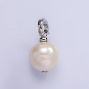 May include: A white pearl pendant with a silver clasp. The pearl is round and has a smooth surface.