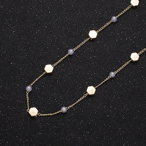 May include: A gold chain necklace with hexagonal charms and small pearl beads.