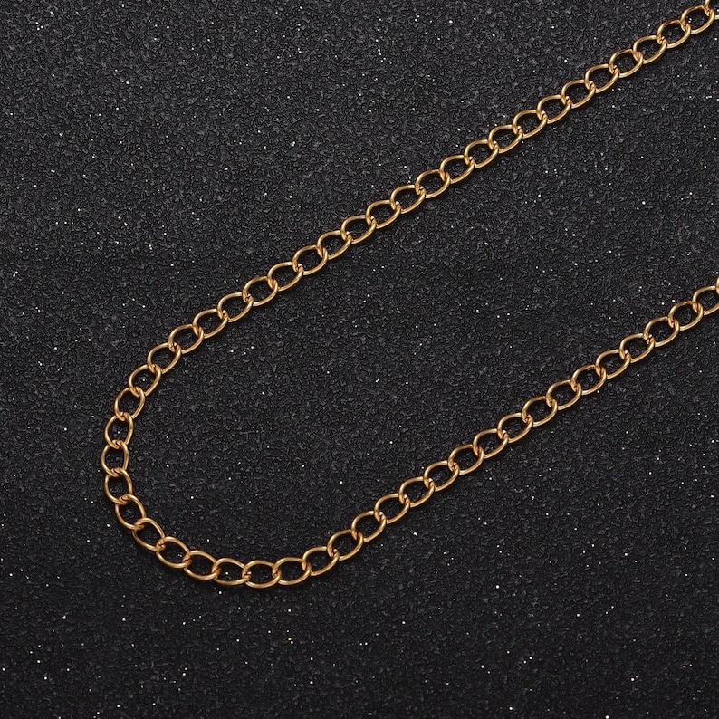May include: A gold chain necklace with a classic curb link design. The chain is on a black background.