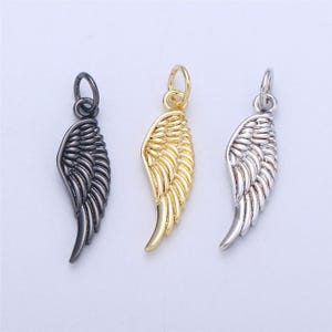 May include: Three angel wing charms in different finishes: black, gold, and silver. Each charm features a detailed wing design.