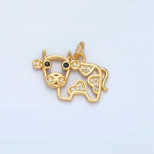 May include: A gold-tone cow charm with black eyes and white cubic zirconia accents.