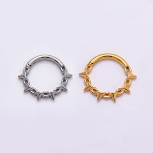 May include: Two circular hinged rings, one in a polished silver tone and one in a polished gold tone. Each ring features a series of evenly spaced, small, pointed spikes protruding outward along the outer edge of the circular band structure.