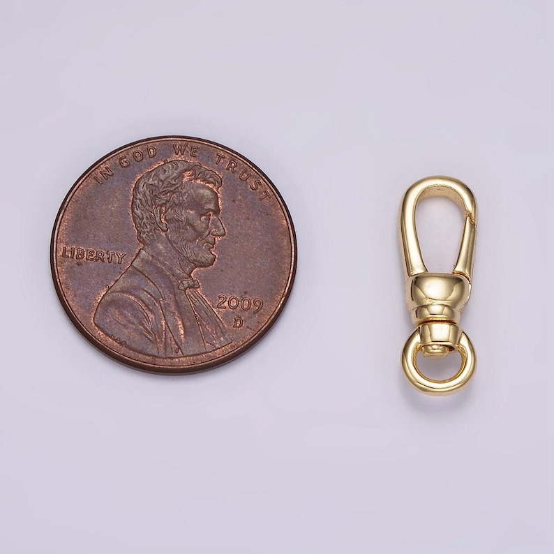 May include: A gold-toned metal swivel clasp, approximately the size of a US penny. The clasp has a spring-loaded gate and a round ring.