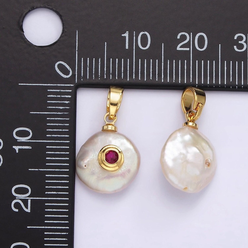 May include: Two gold-tone pendants with a baroque pearl and a red gemstone. The pearl pendant is about 1.5 inches in diameter. The pendant with the gemstone is about 1 inch in diameter.