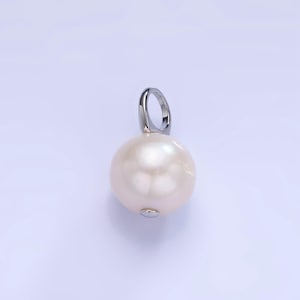 Può includere: Un ciondolo di perla bianca con un'anellina d'argento.